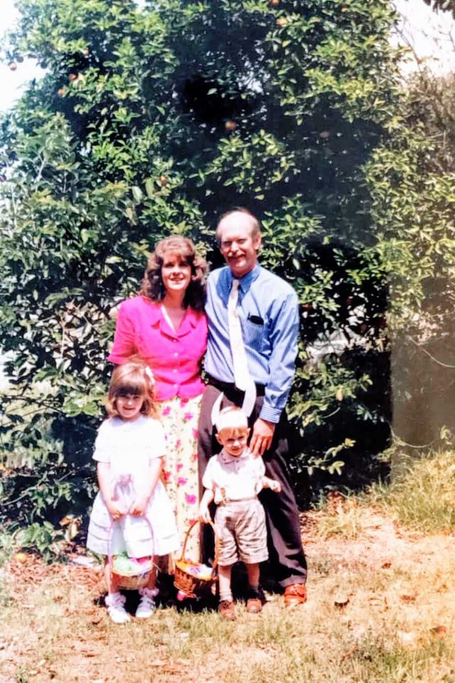 Little girl unknowingly battling autism poses for a family photo in her Sunday best while standing in front of a big tree