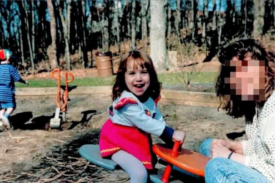 Young girl rides on a seesaw with her narcissistic mother at the playground