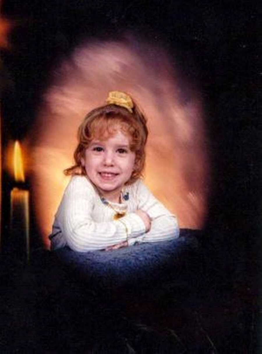 Little girl experience sexual abuse at home smiles for a photo with a sunset backdrop and a candle next to her