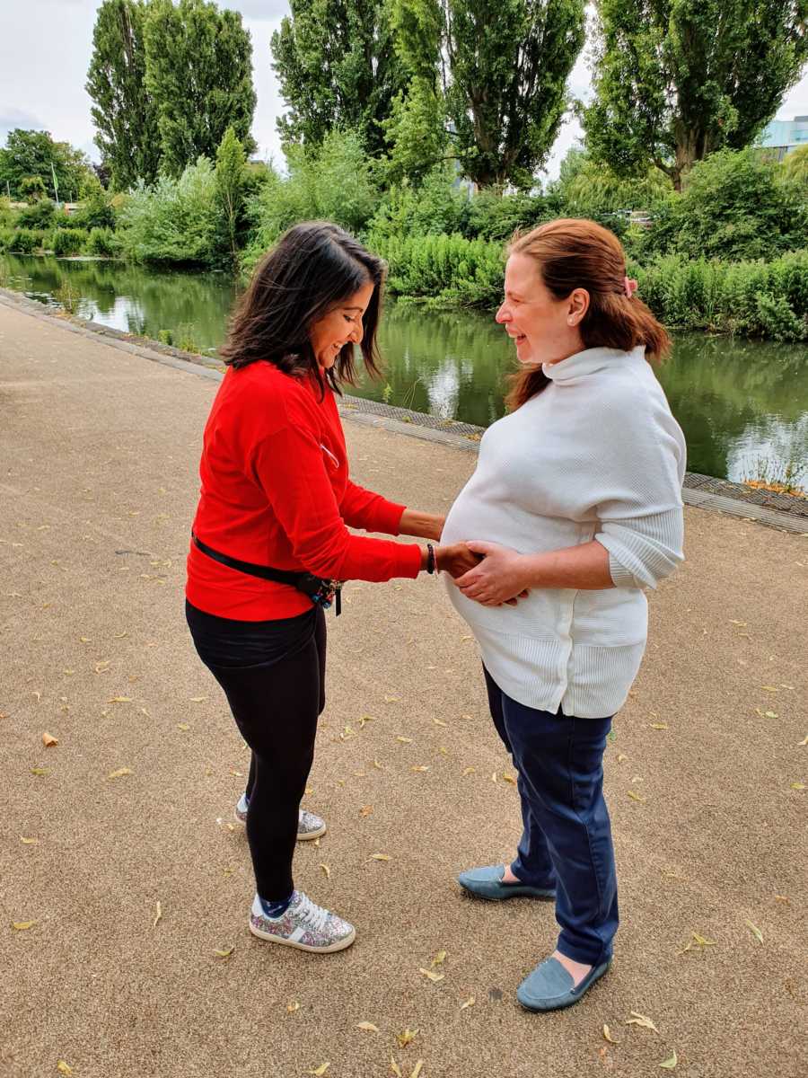 Woman holds the belly of her surrogate, pregnant with triplet boys