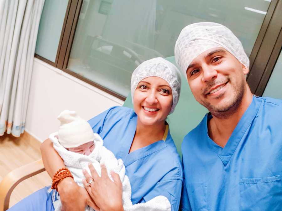 Intended parents hold their newborn daughter conceived via embryo transfer through a surrogate