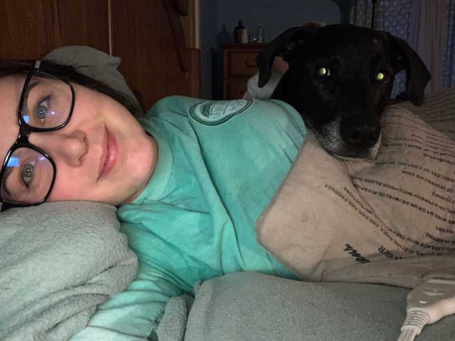 woman laying in bed with her dog