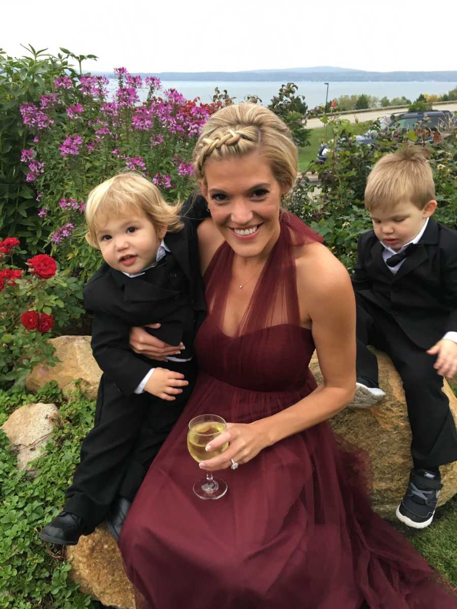 A woman holds a wine glass while sitting with her two sons