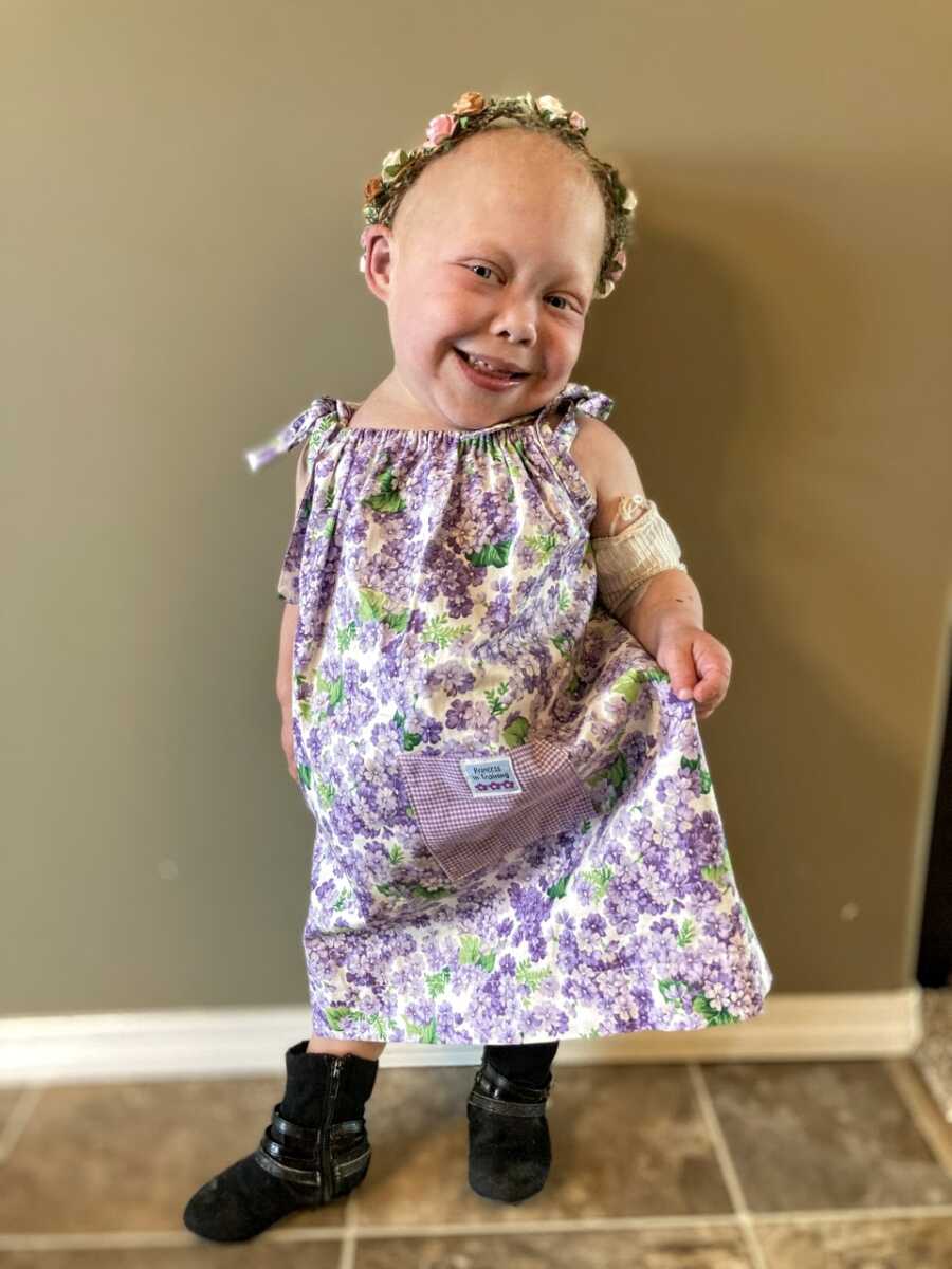 Medically complex little girl smiles and poses in a floral dress with a flower crown