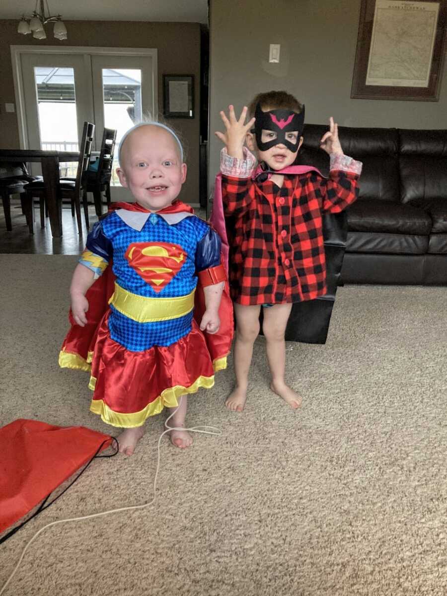 Little girl born with multiple rare conditions poses in a Superwoman costume next to her little brother