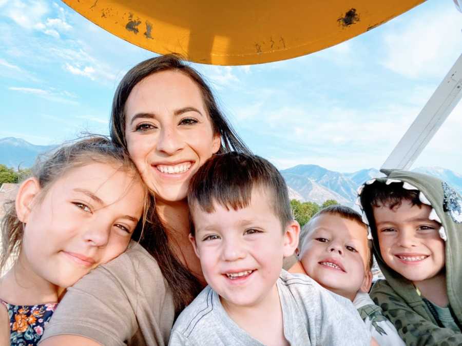 Single mom takes a selfie with her 4 kids while on a ferris wheel with mountains in the background