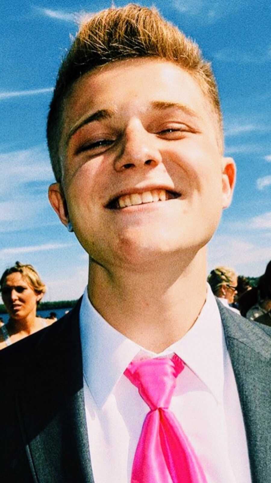 Mom snaps an up-close photo of her son in high school while taking prom pictures in a suit and pink tie