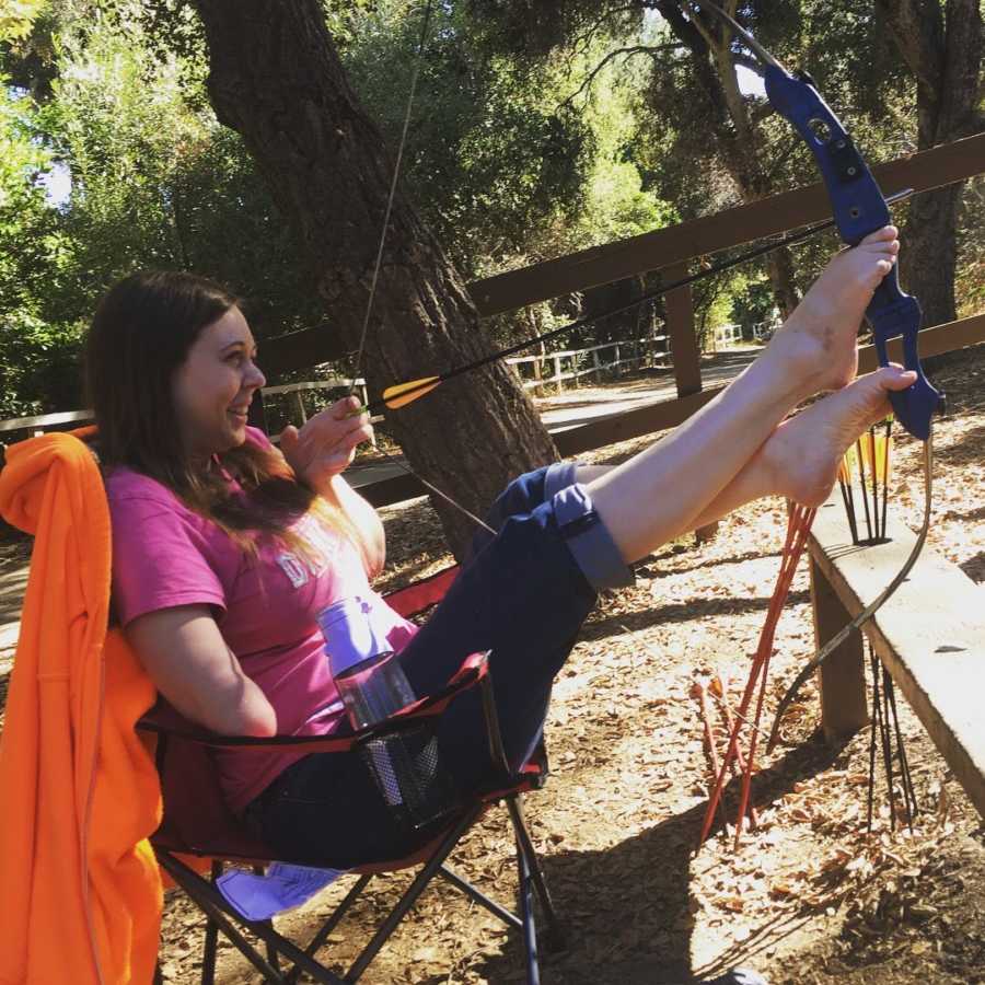 woman with one arm doing archery with her feet