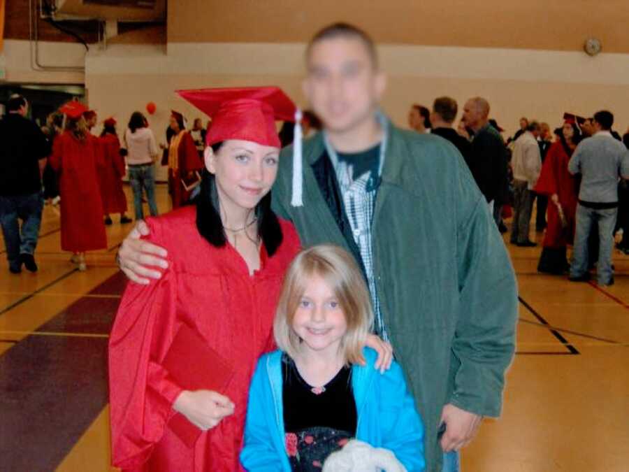 Teen mom graduates from high school in a red cap and gown