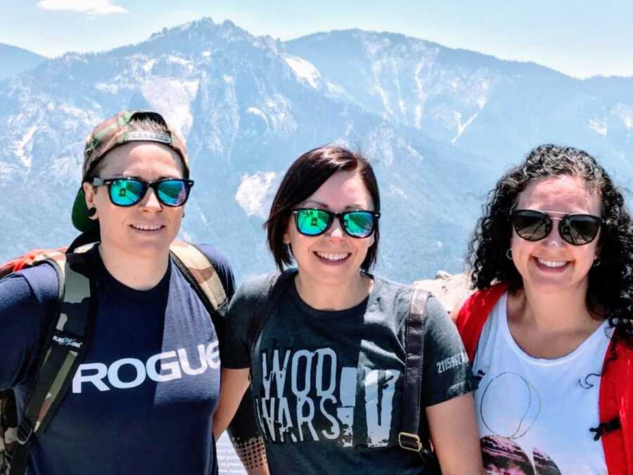Woman diagnosed with autism and ADHD as an adult poses for a photo with her friend and her partner while standing in front of a mountain