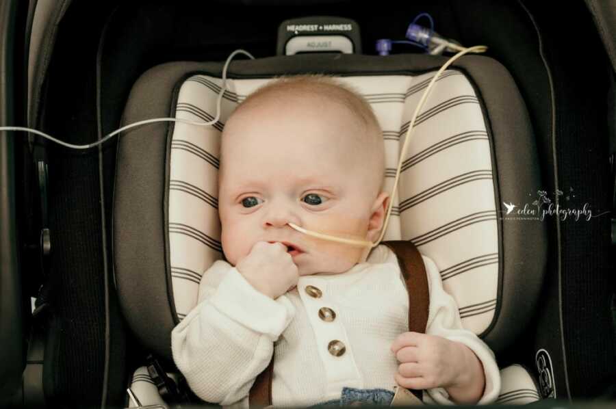 Little boy with rare Trichohepatoenteric syndrome sits in a car seat while attached to oxygen tube