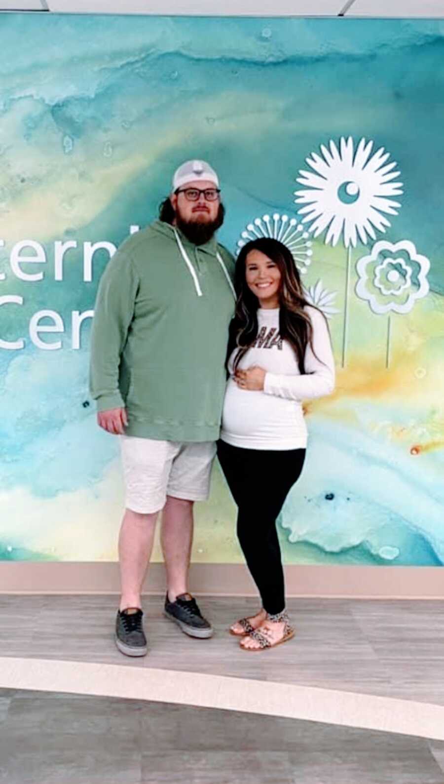 Couple expecting their second son together take a photo while showing off the woman's baby bump