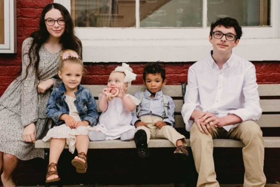 Parents take photos of their five children all sitting together on a bench to celebrate the adoption of their youngest child