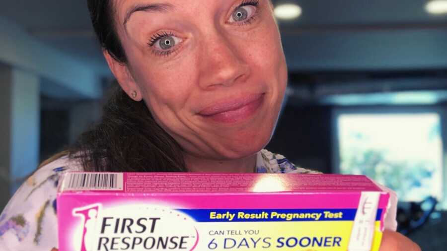Woman holding up first response pregnancy test box