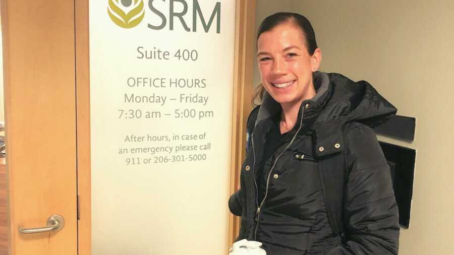 Woman in coat standing next to office door