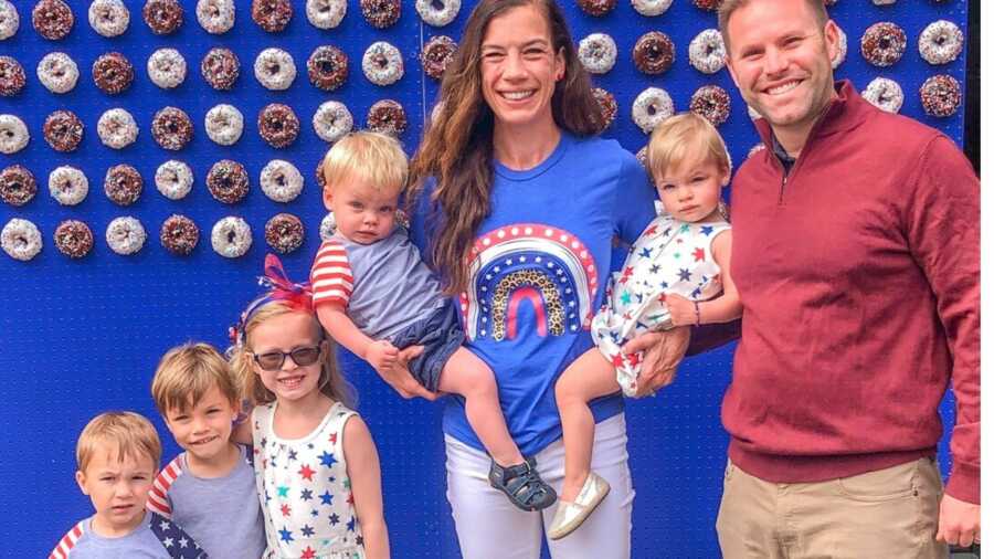 Family of seven dressed in red white and blue in front of donut display