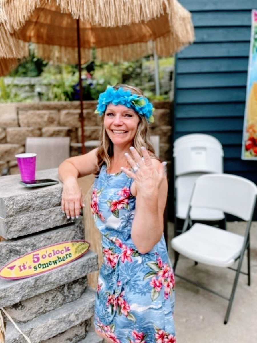 Woman smiles big and shows off her wedding ring at her Luau-themed surprised wedding 