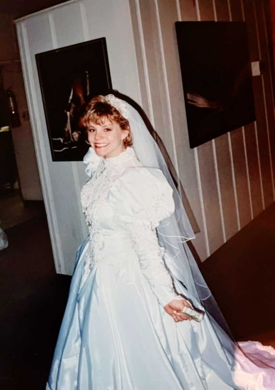 Young woman in traditional wedding gown smiles big during her wedding ceremony