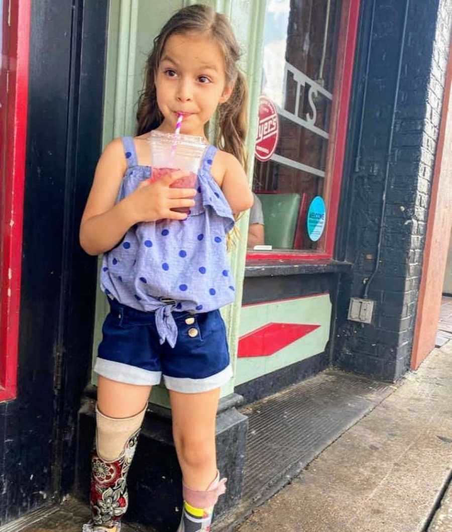 Little girl with a limb difference looks sassy while drinking a smoothie