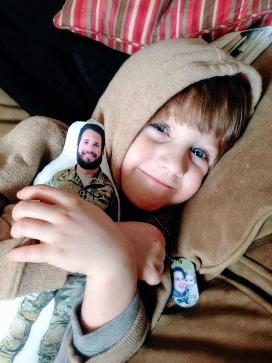 Little boy cuddles with a dog tag and a doll of his dad off serving in the war in Afghanistan