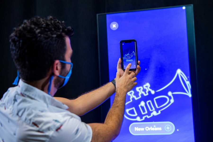 Man wears a mask and uses his phone for the Disney Unchartered Adventure experience aboard the new Disney Wish cruise ship