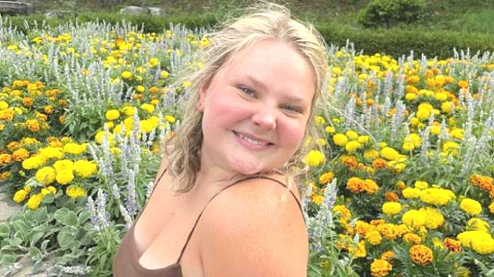 Woman struggling with mental health stands by flowers