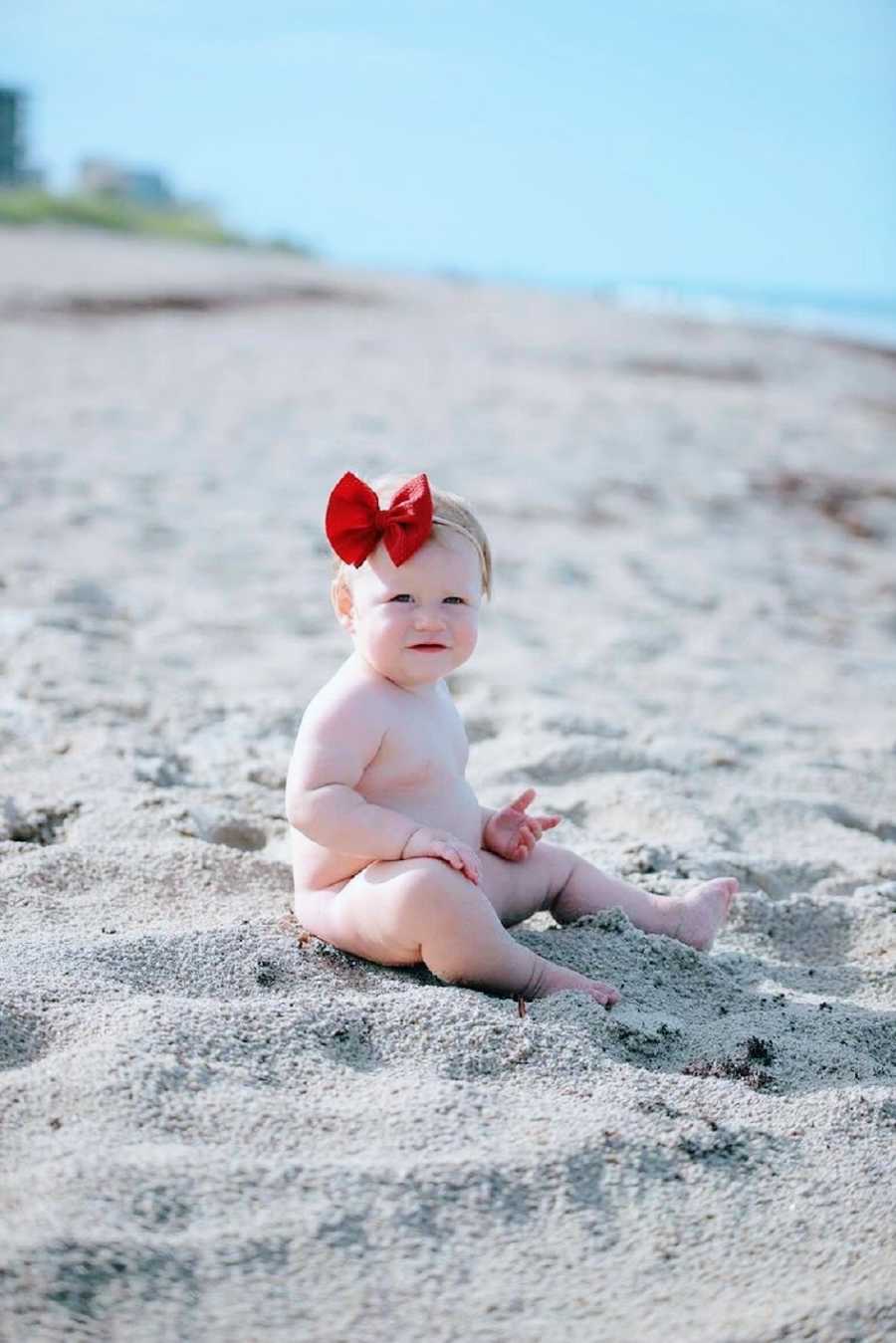 A little girl sits alone in the sand