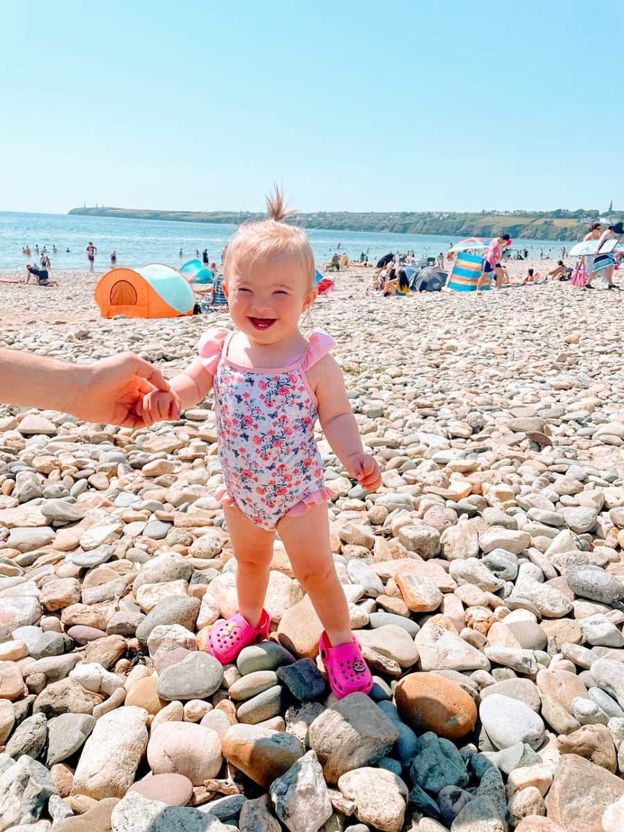 A little girl stands on a rocky beach