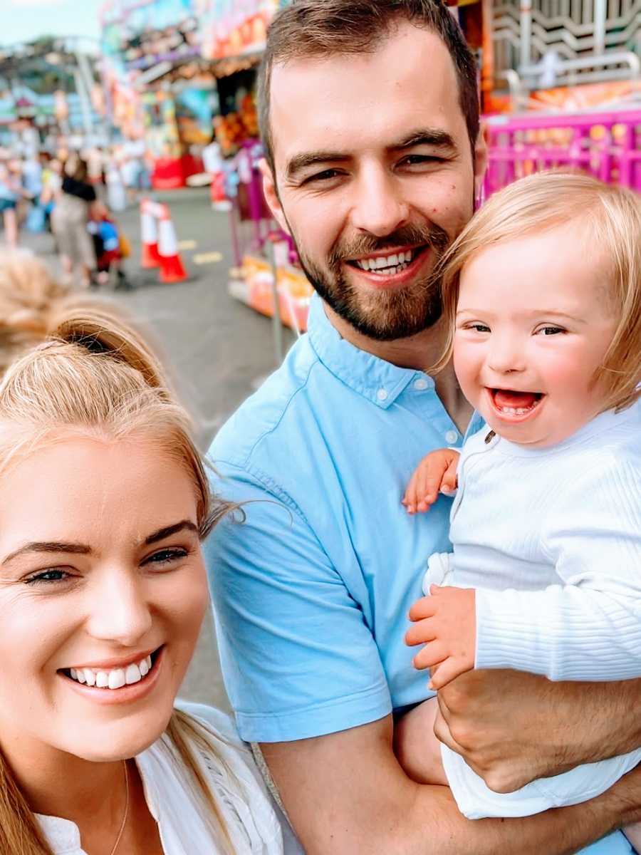 Parents hold their baby girl outside