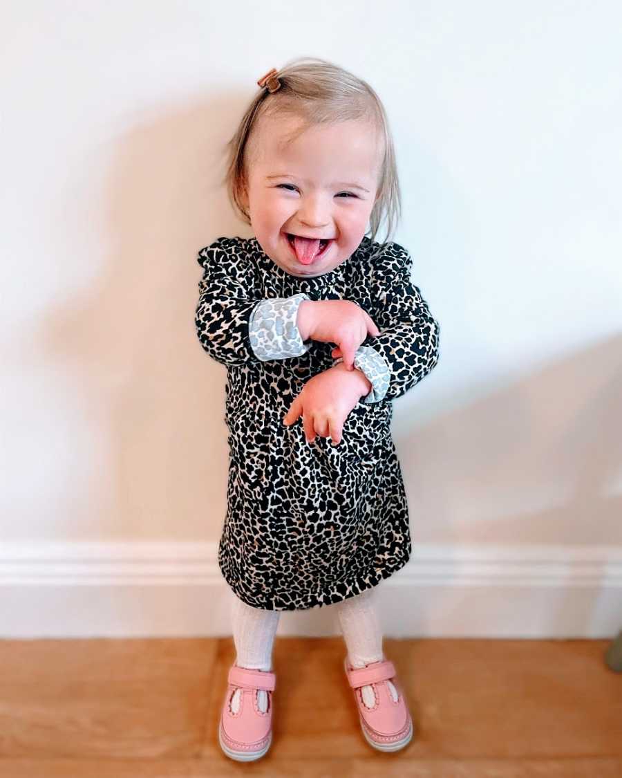 A little girl wearing a leopard-print dress makes a silly face