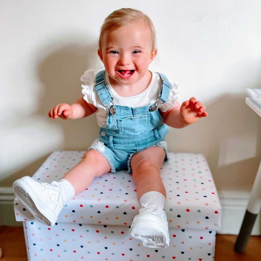 A little girl with Down Syndrome wearing overalls