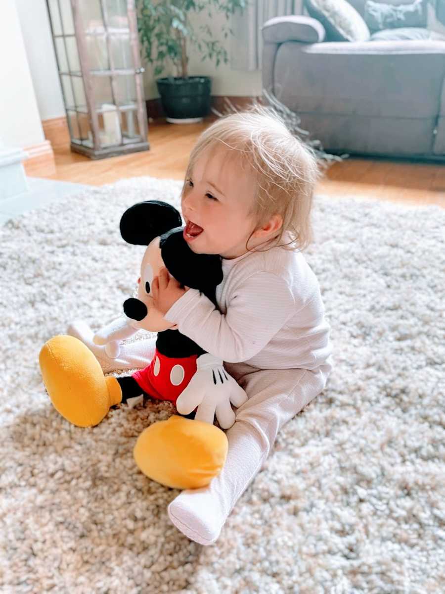 A baby girl holds a Mickey Mouse toy