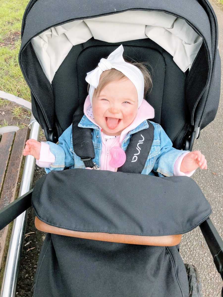 A baby girl with Down Syndrome sits in a stroller