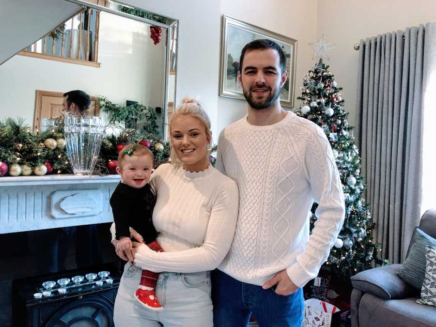 Parents wearing white hold their baby girl at Christmas