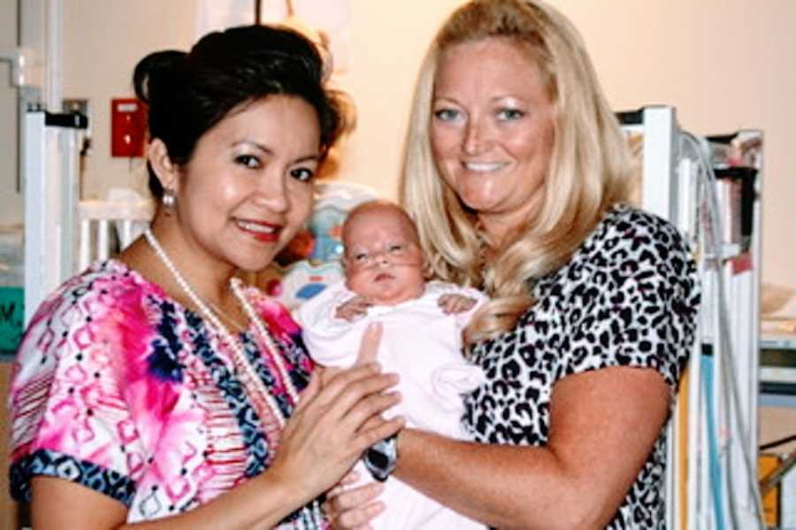 A pair of NICU nurses hold up a tiny baby girl