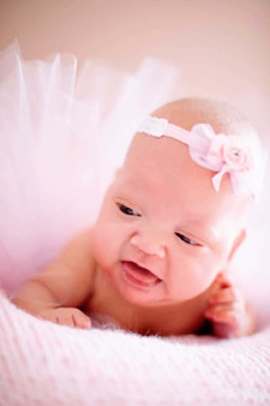 A baby girl wearing a pink dress and headband