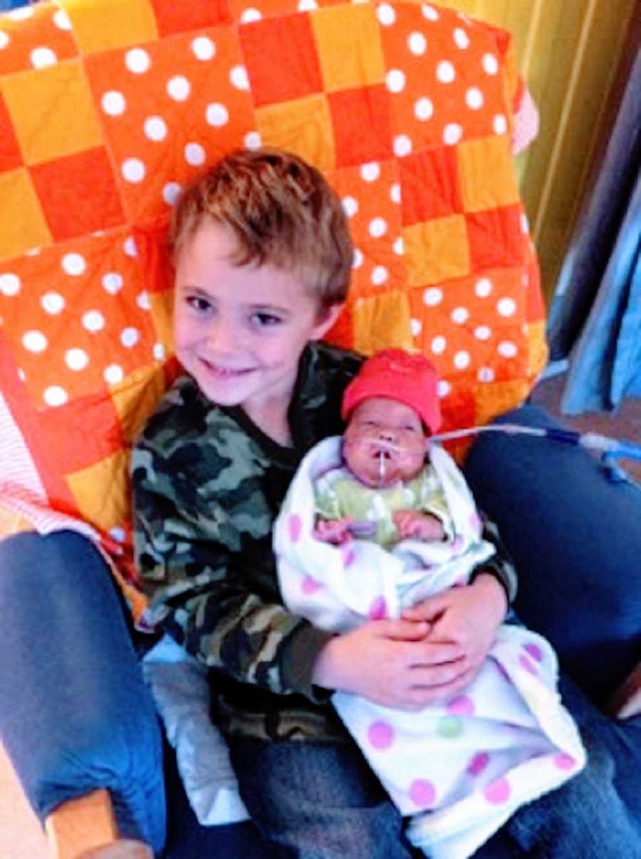 A little boy holds his baby sister in the hospital