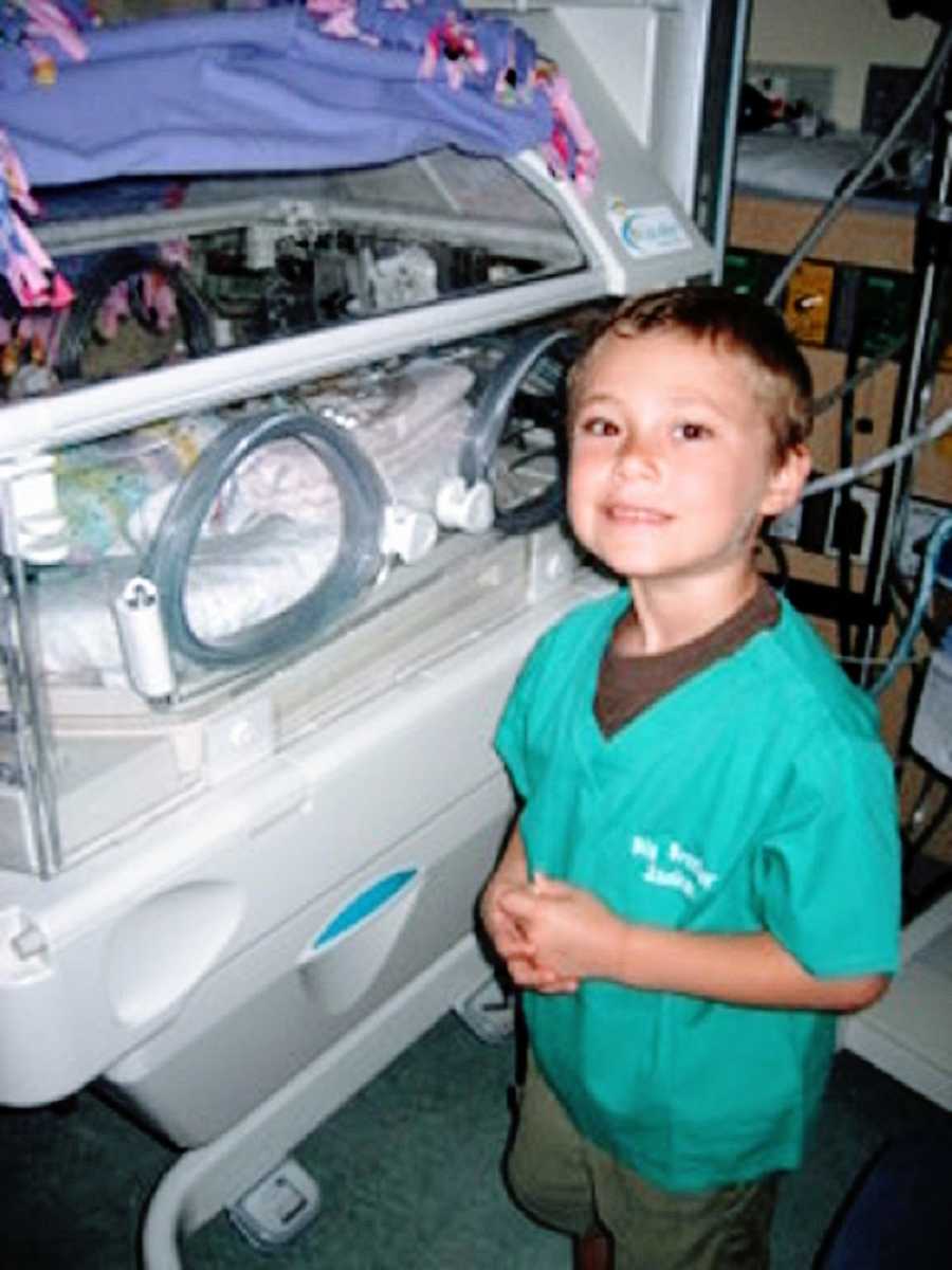 A little boy stands in the NICU visiting his baby sister