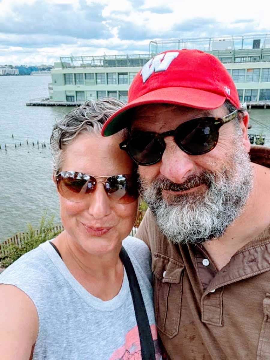 A woman and her husband stand together by the water