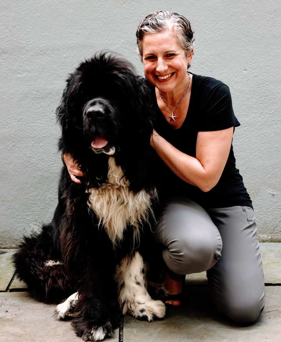 A woman sits with her big black Newfoundland