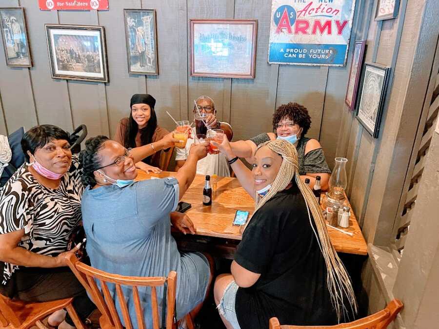 Woman sits with others at a table holding their glasses up