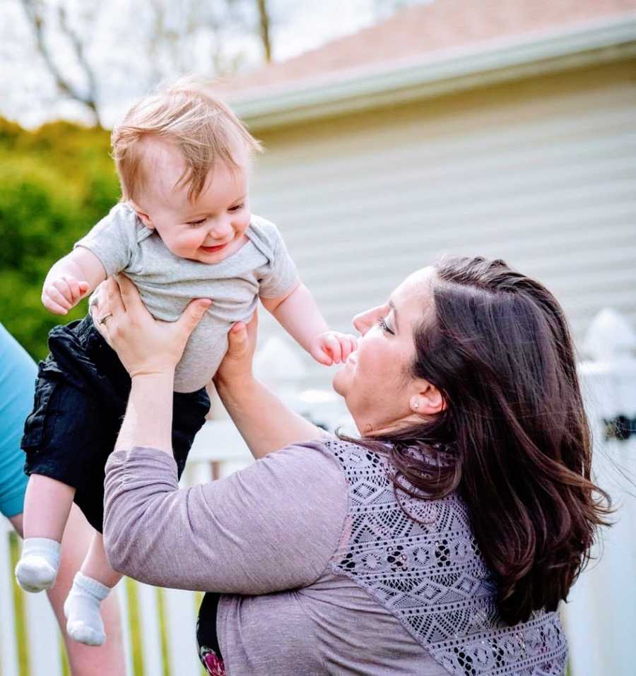 A mother holds her young son up in the air