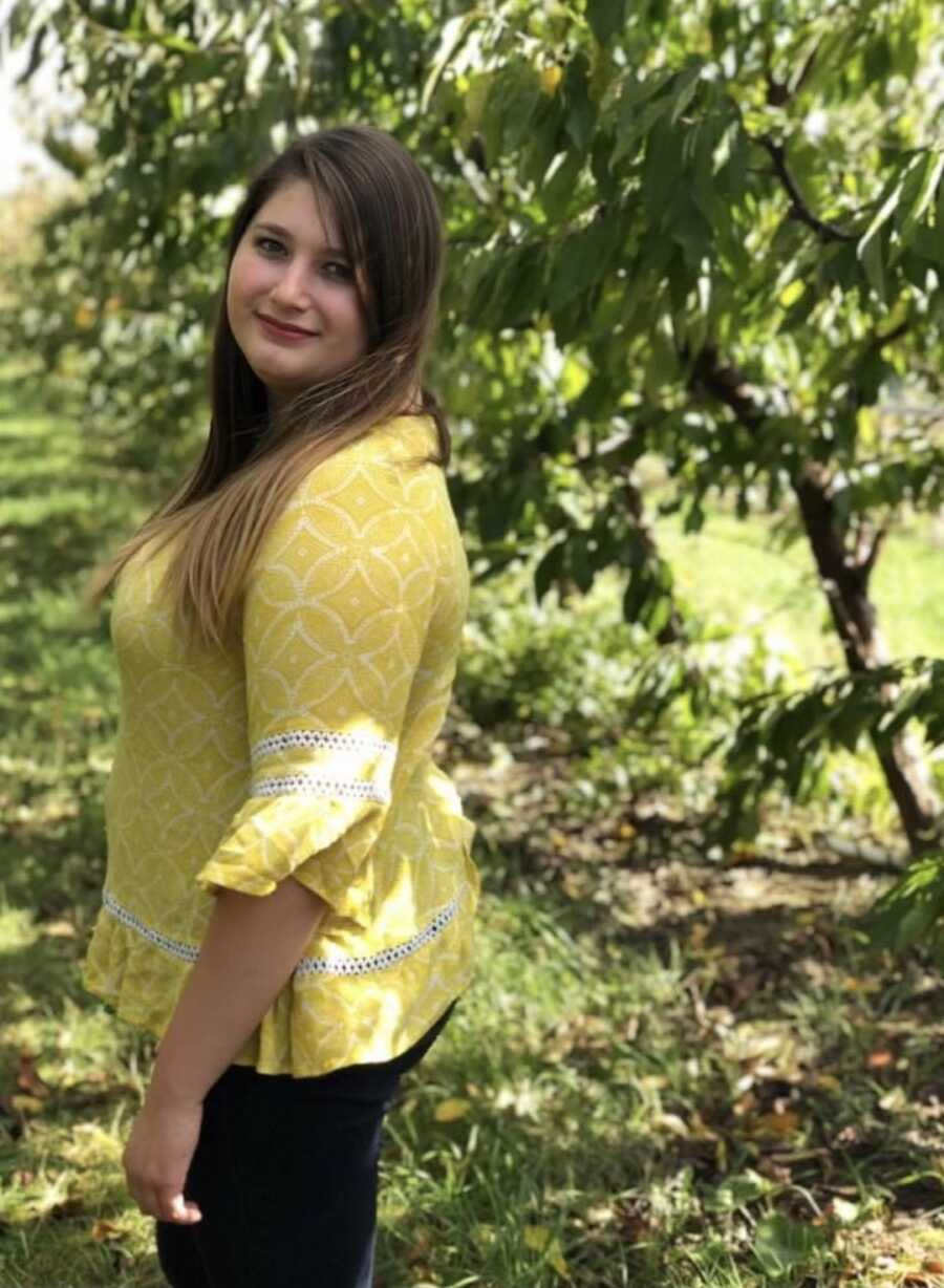 woman standing next to trees proud