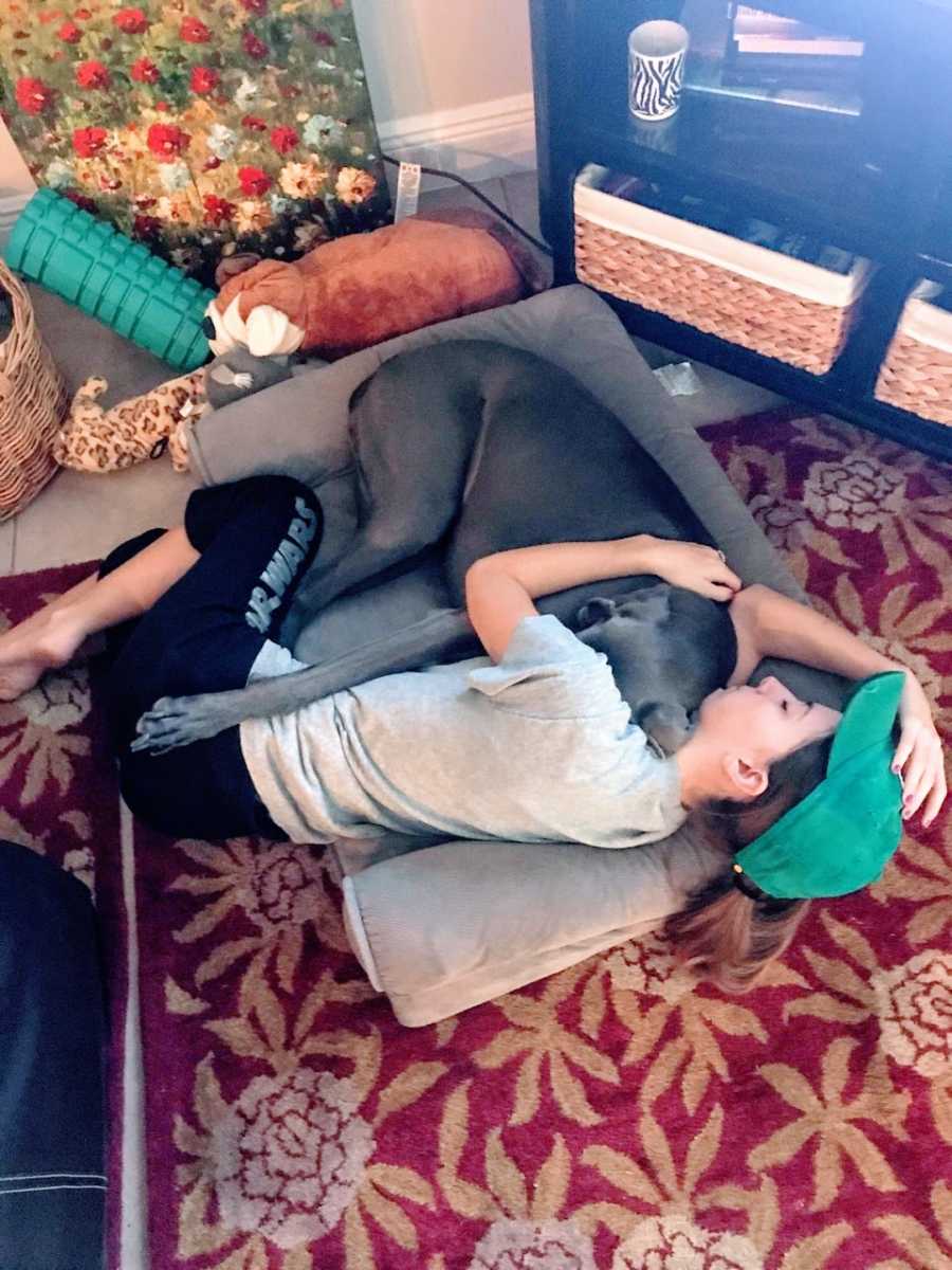 Spinal tumor survivor lies on the floor with dog