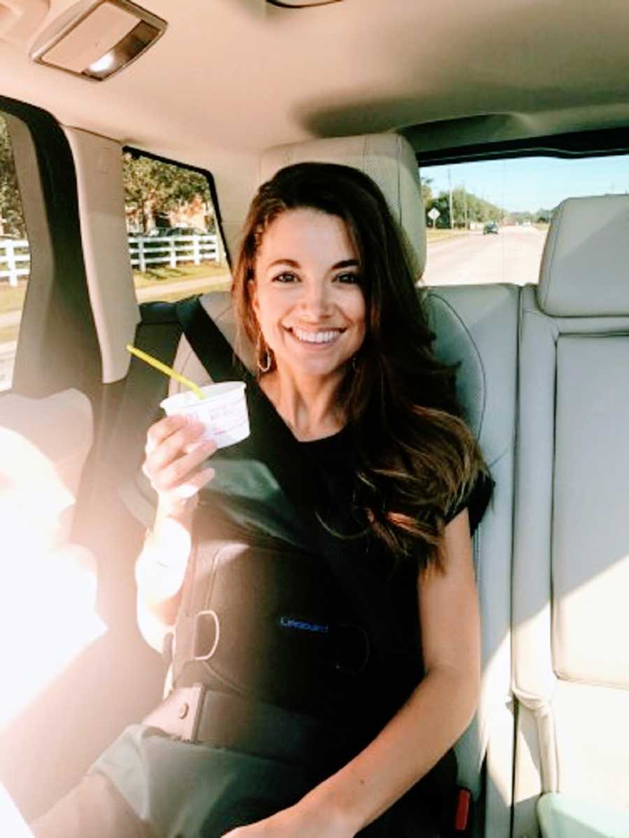 Woman sits in car holding cup of food