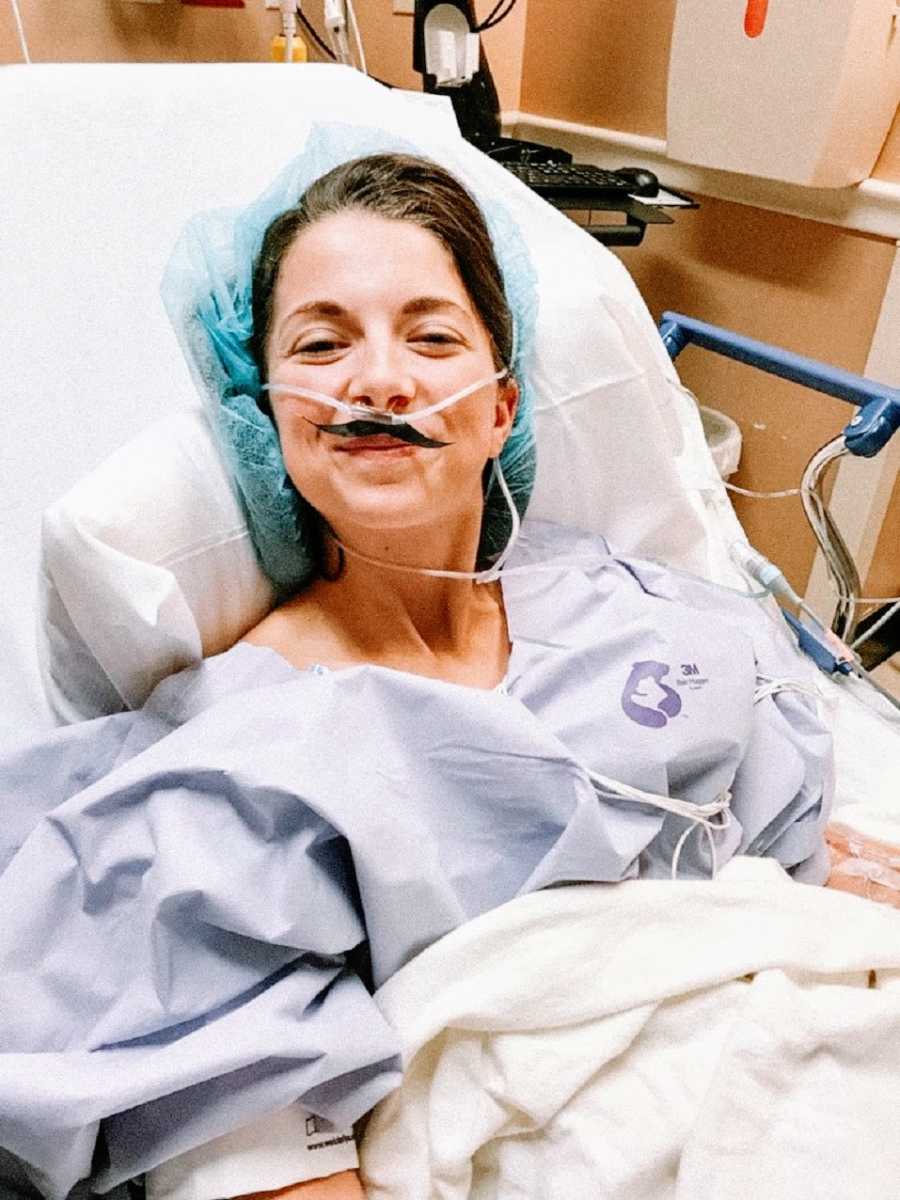 Spinal tumor survivor wears tubes and paper moustache