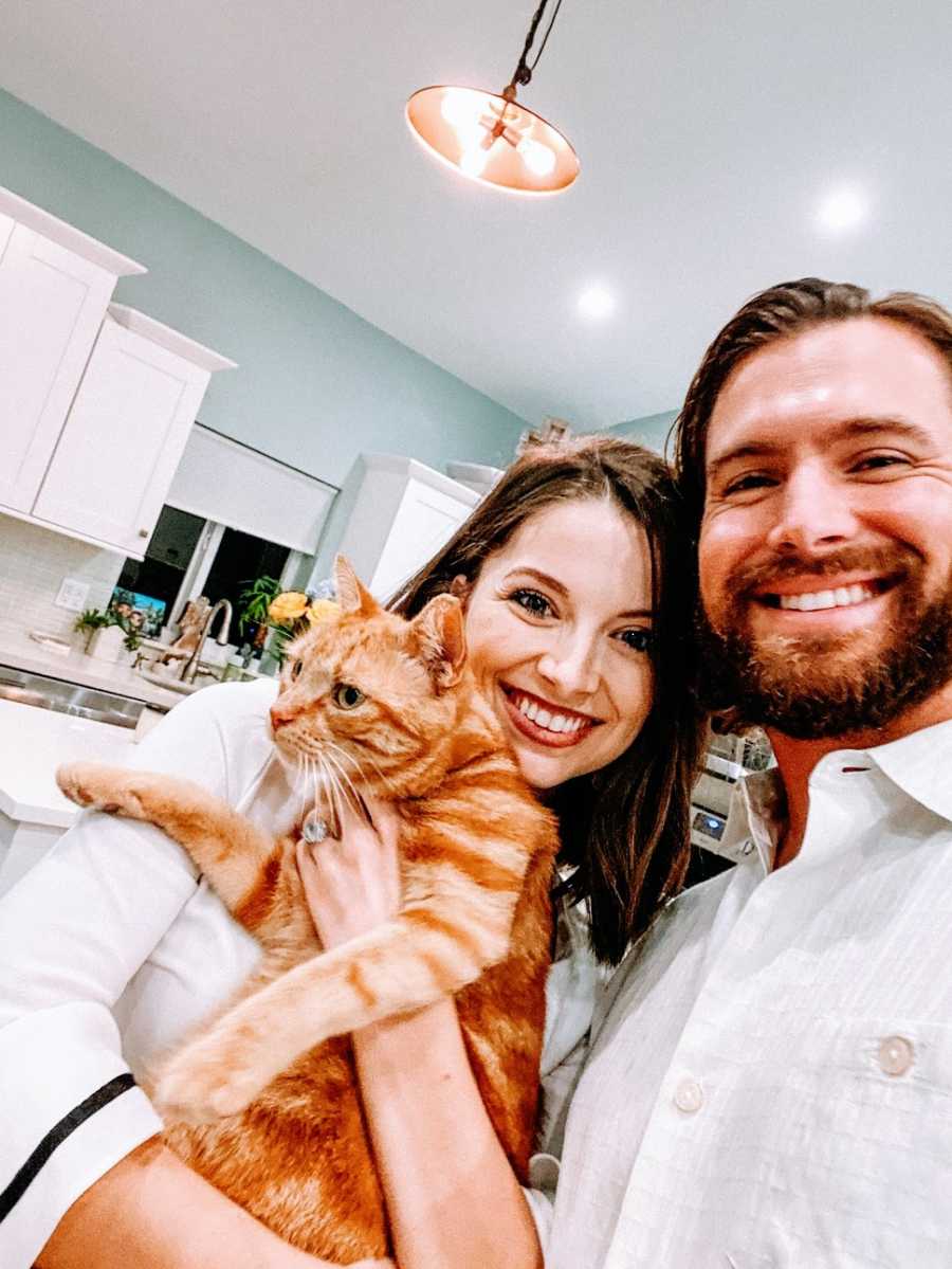 Woman and husband in kitchen holding cat