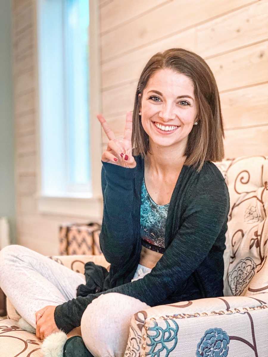 Woman sits giving peace sign
