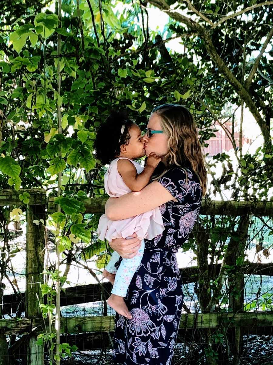 A mother gives her baby girl a kiss on the lips