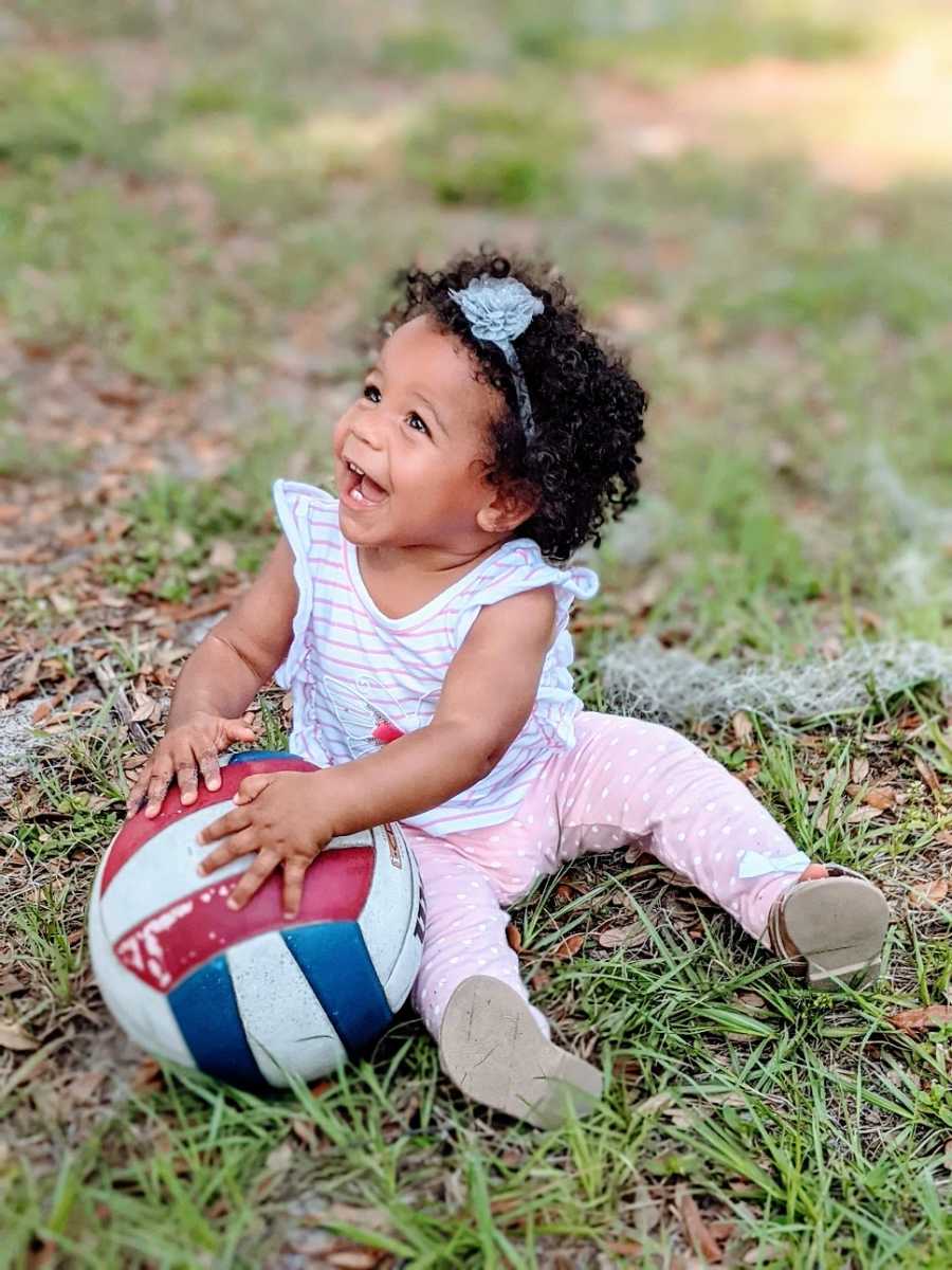 A little girl plays with a volleyball